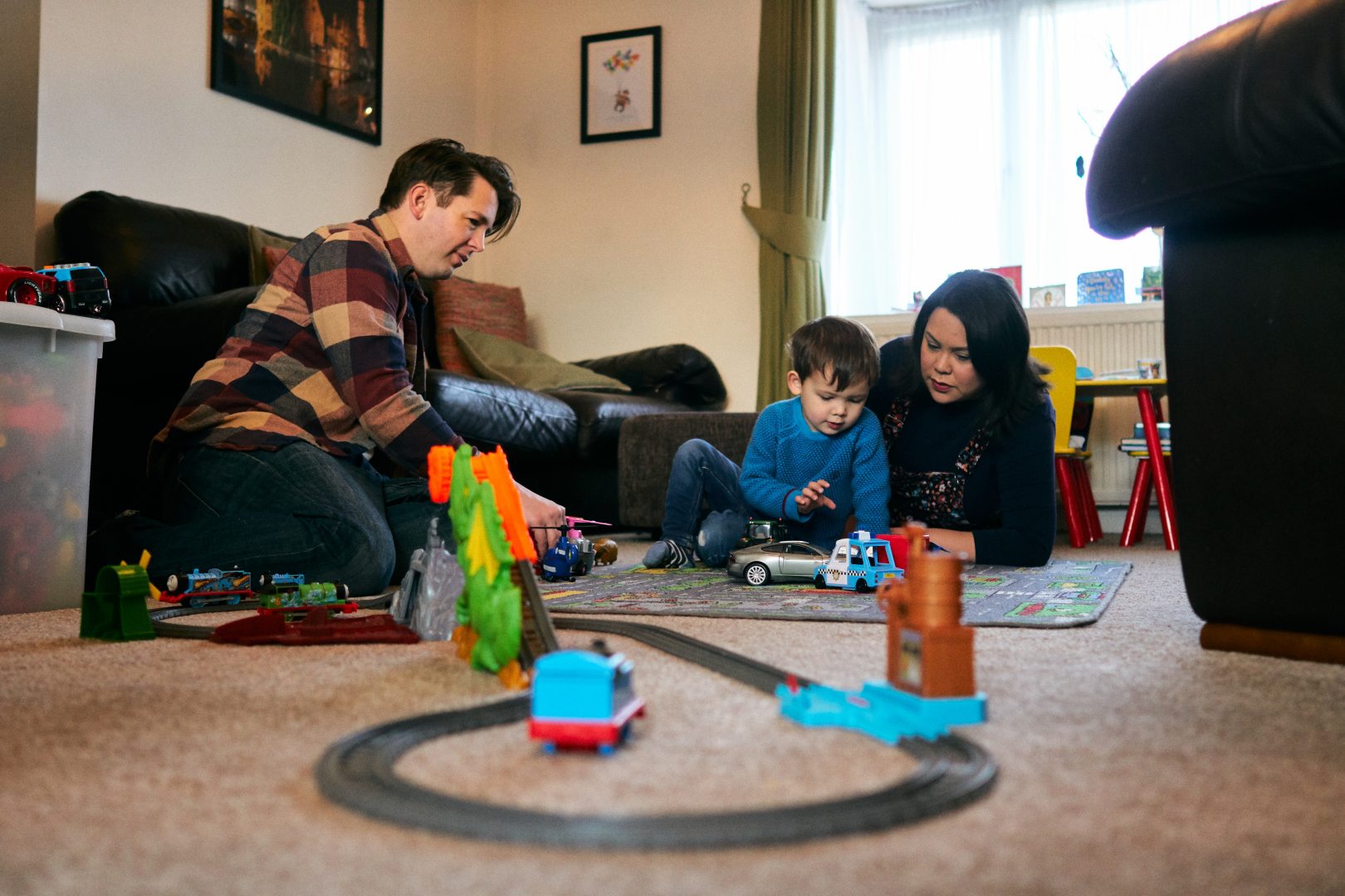family photo of mum dad and son playing on the car mat