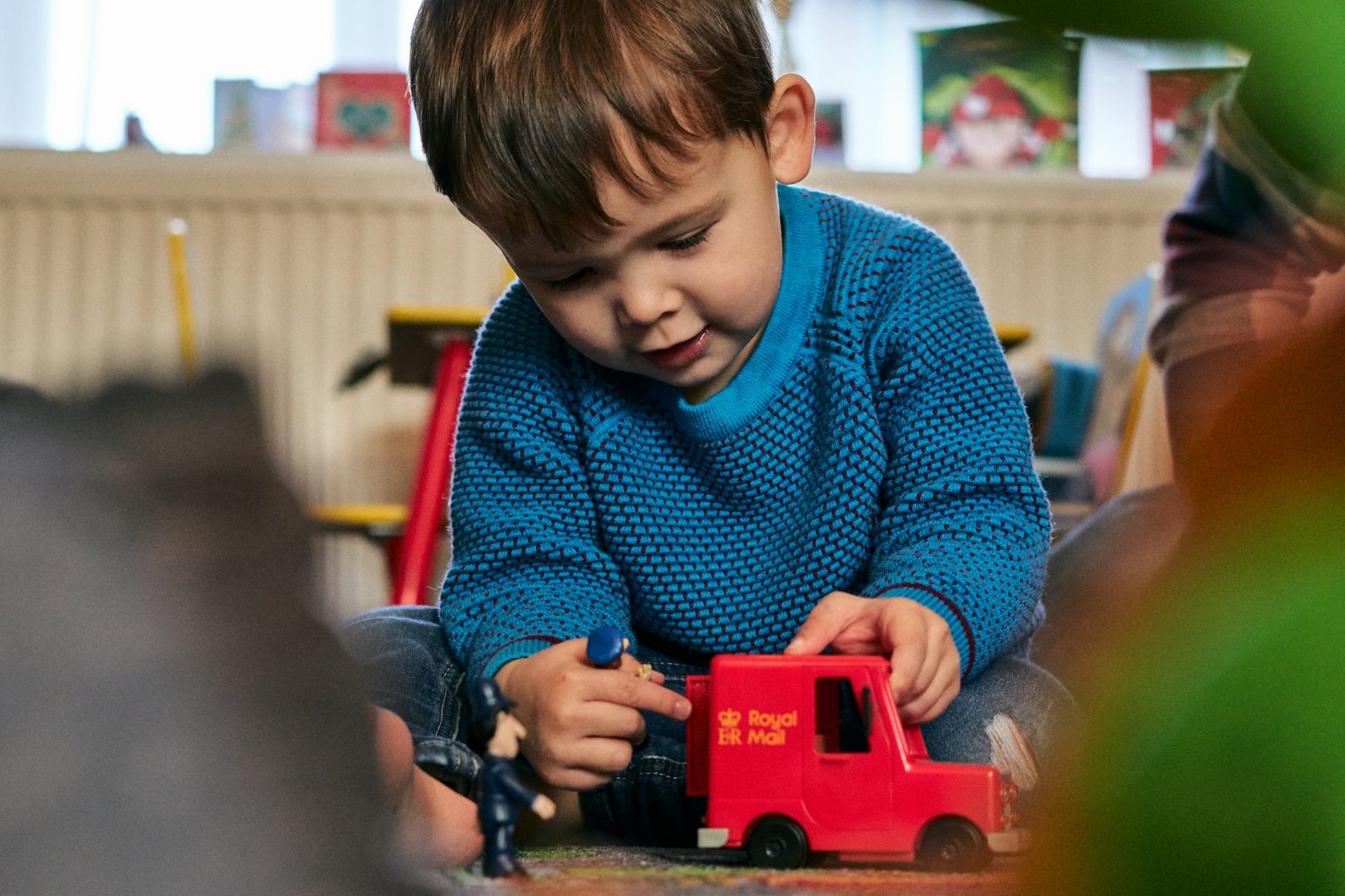 3 year old boy plays with postman pat red van