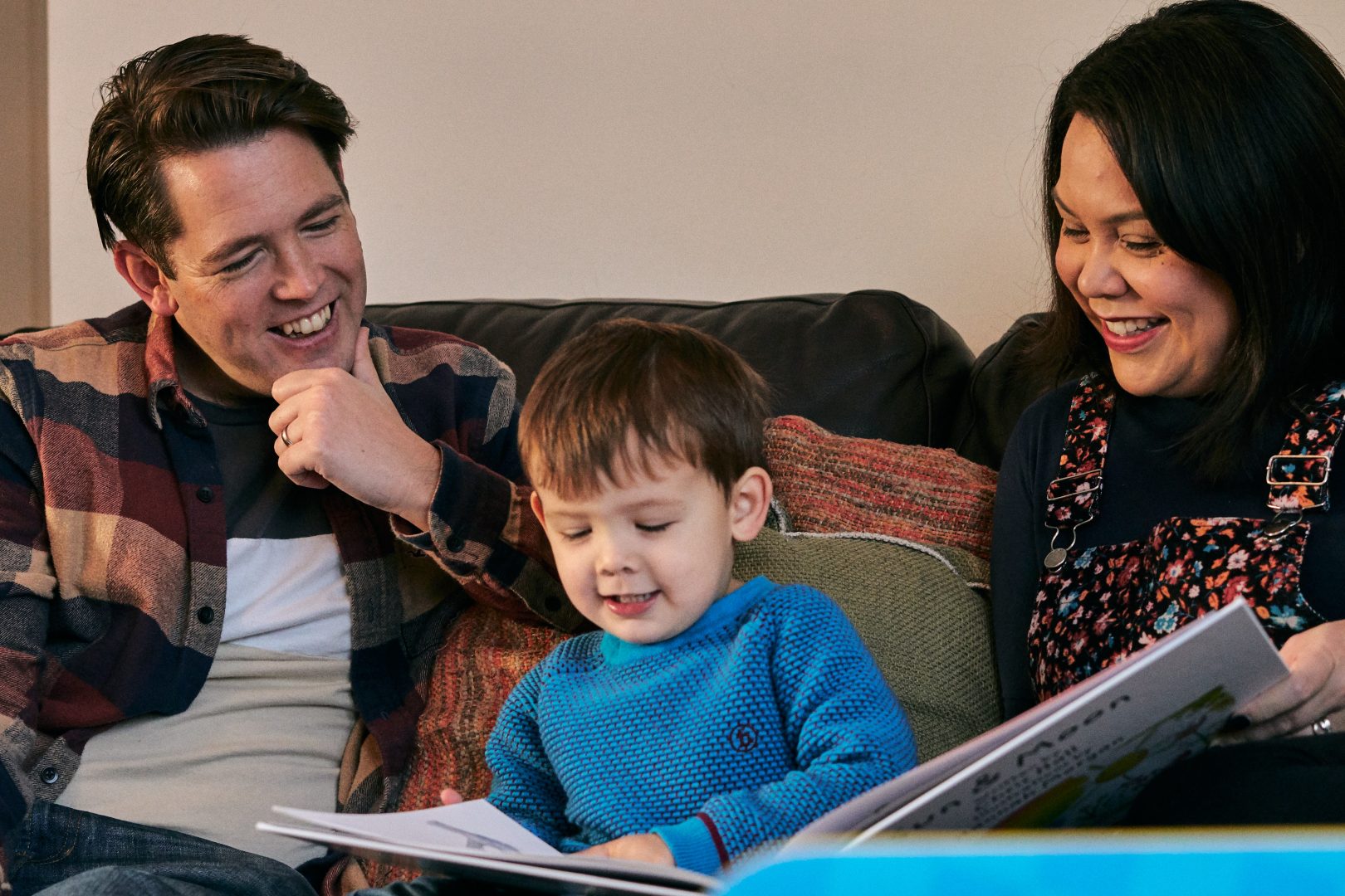 dad mum and son on sofa reading during family photoshoot
