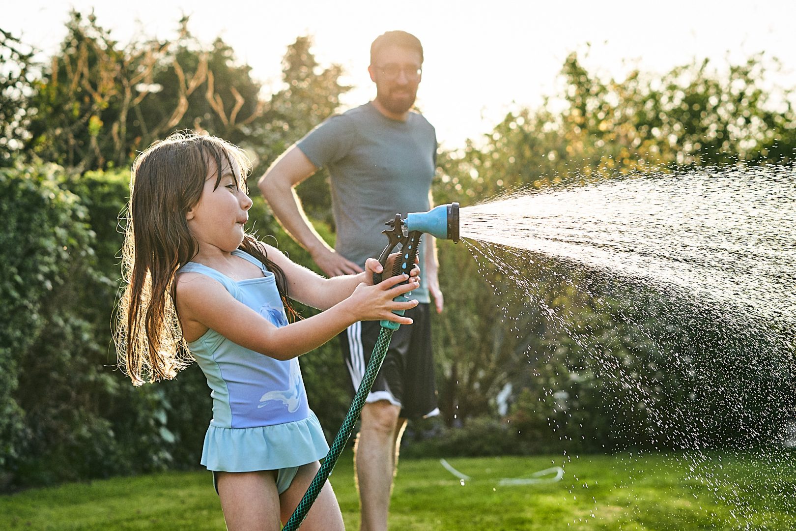 funny photo of girl spraying hose in garden in lancashire