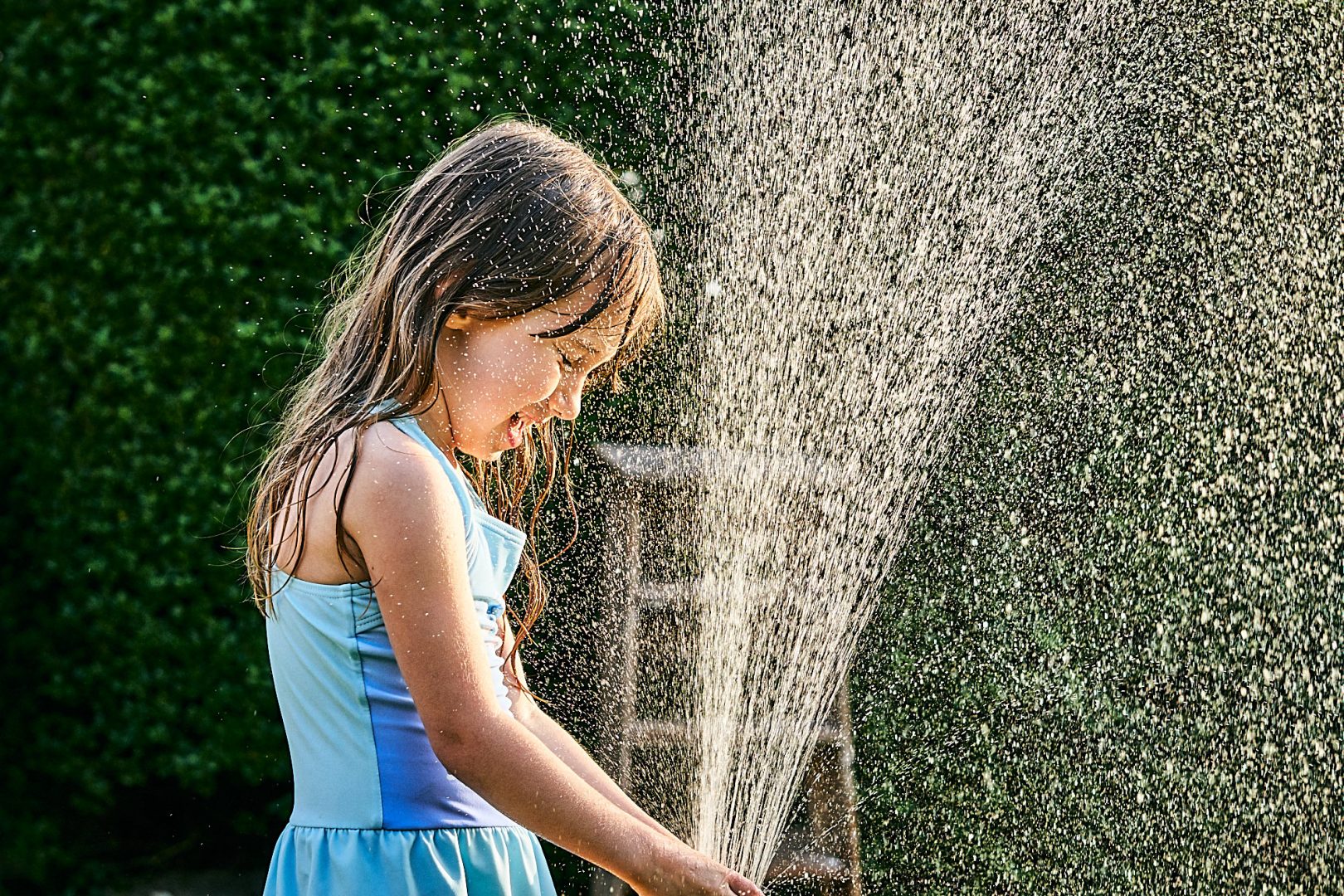 girl plays with hose in garden for photos