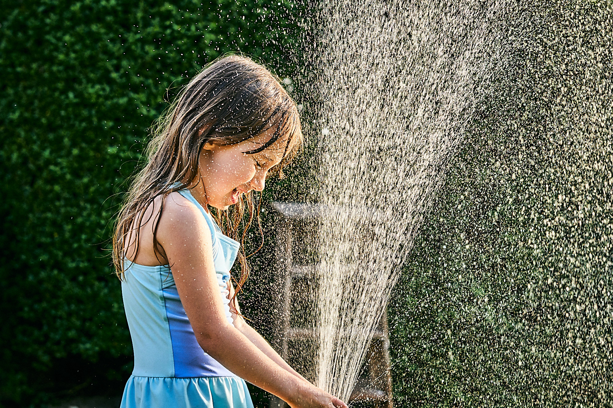 girl plays with hose in garden for photos