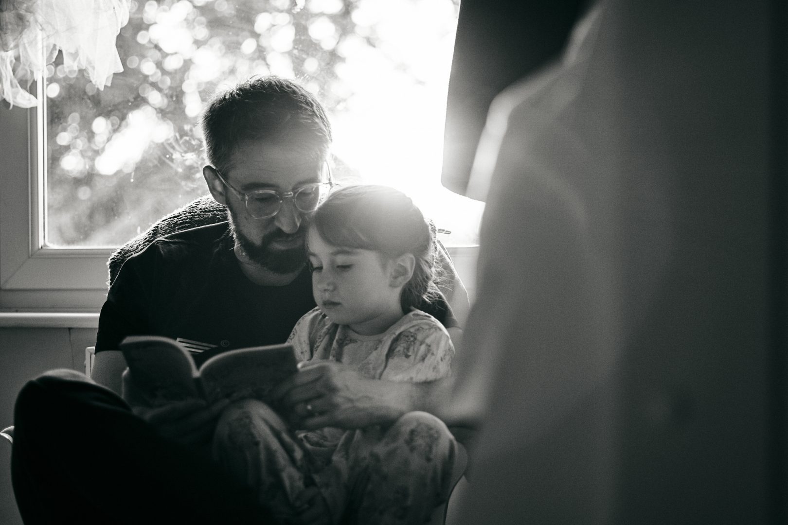 dad and daughter cuddle and read together