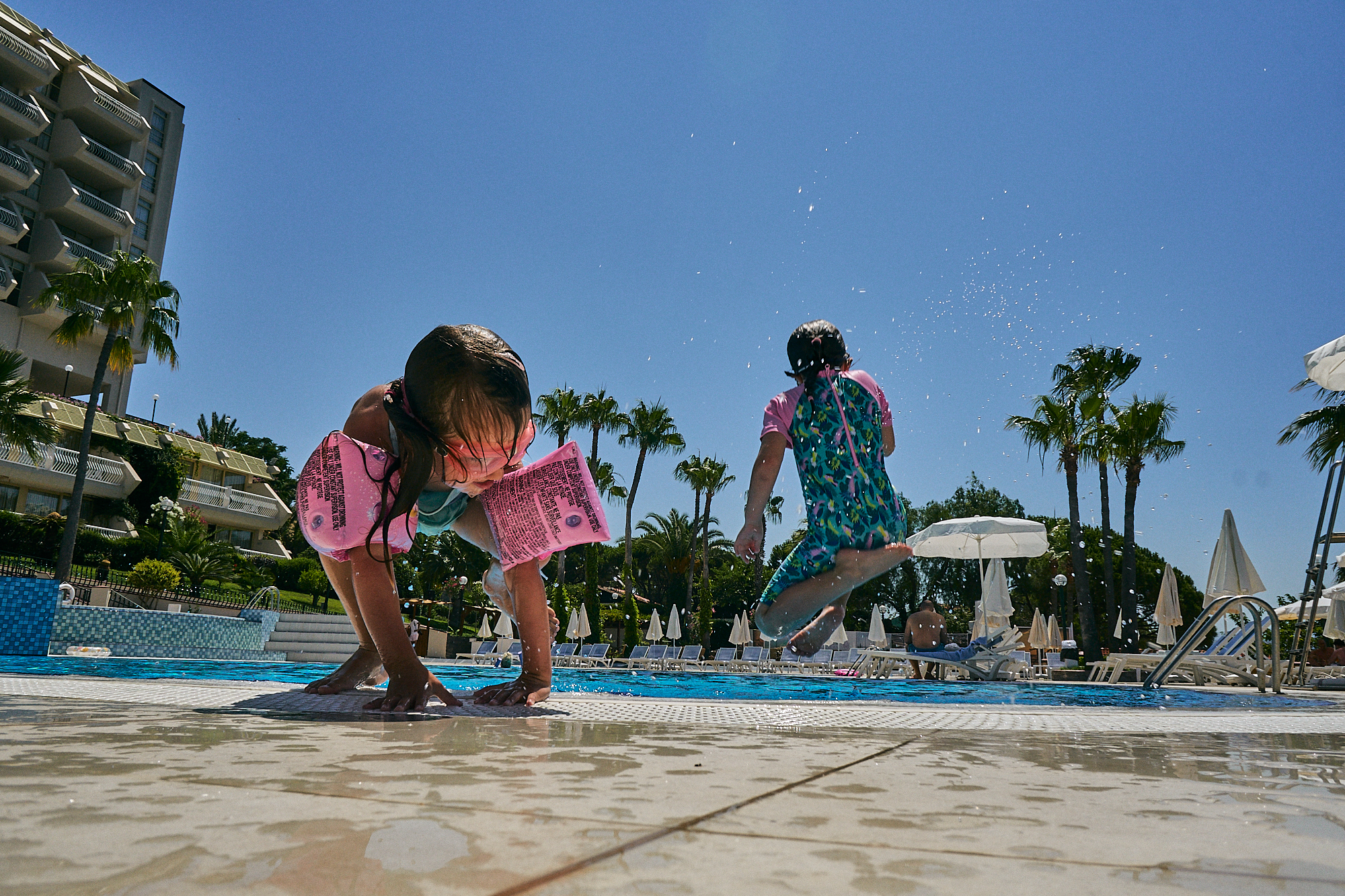 children jumping in swimming pool on holiday