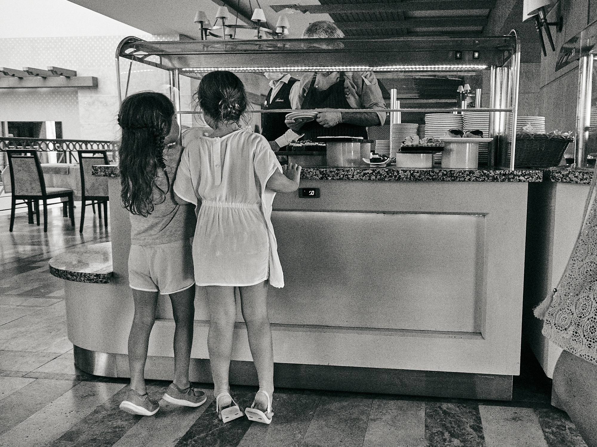 children on tip toes waiting for buffet at hotel