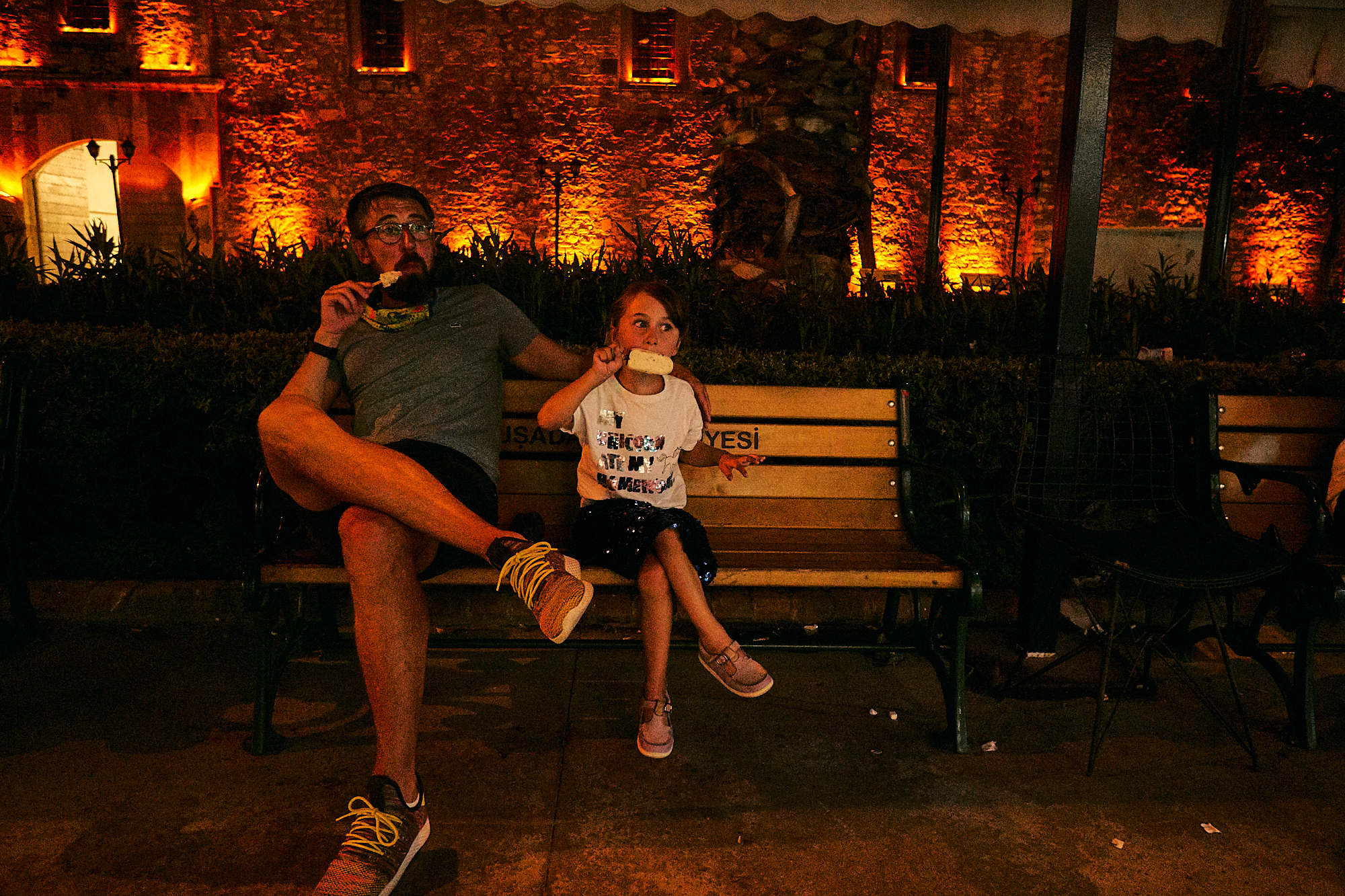 dad and daughter sit on bench eating ice cream