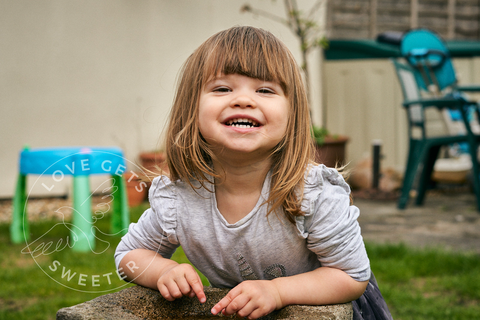 little girl grins at camera in fun family photo