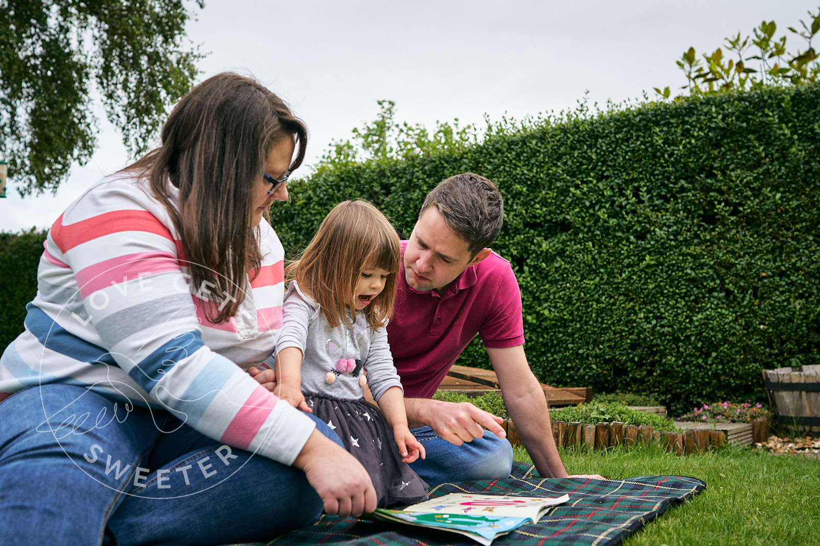 family relax on blanket in garden reading