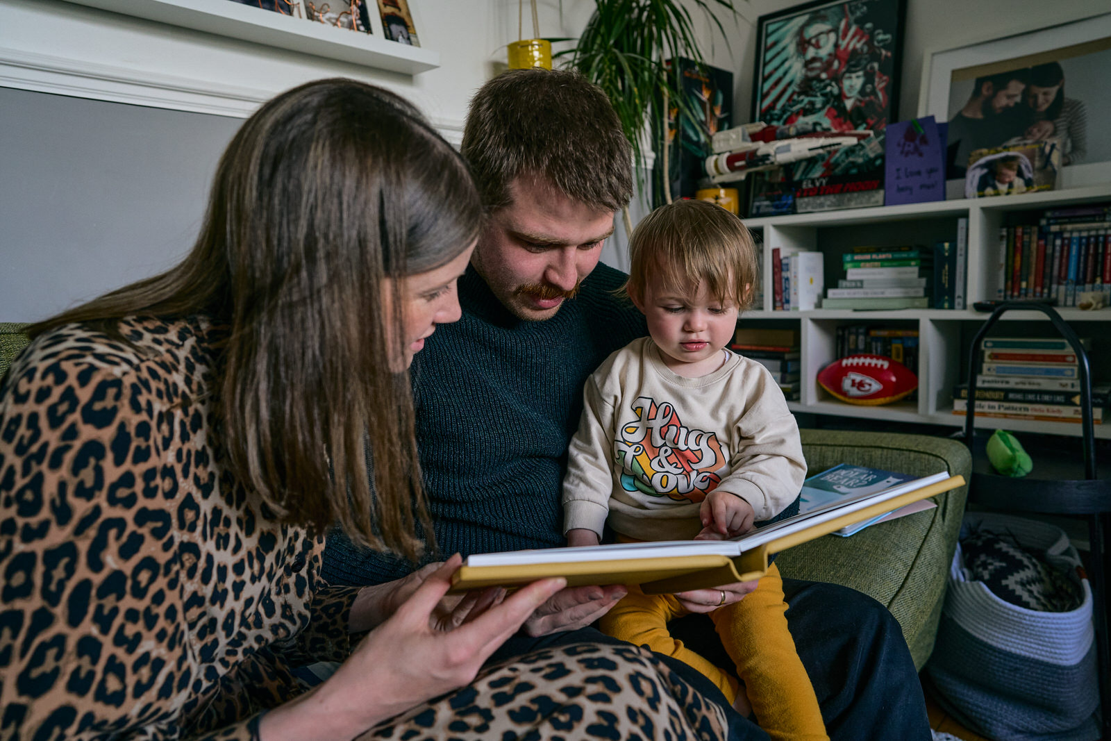 a family sit down together to look over a printed family album at home in Walkden