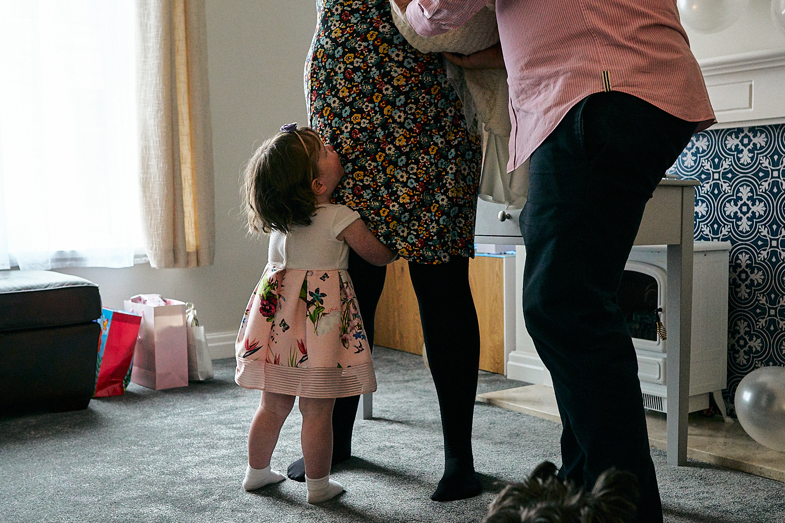 child holds mums leg during naming ceremony at home