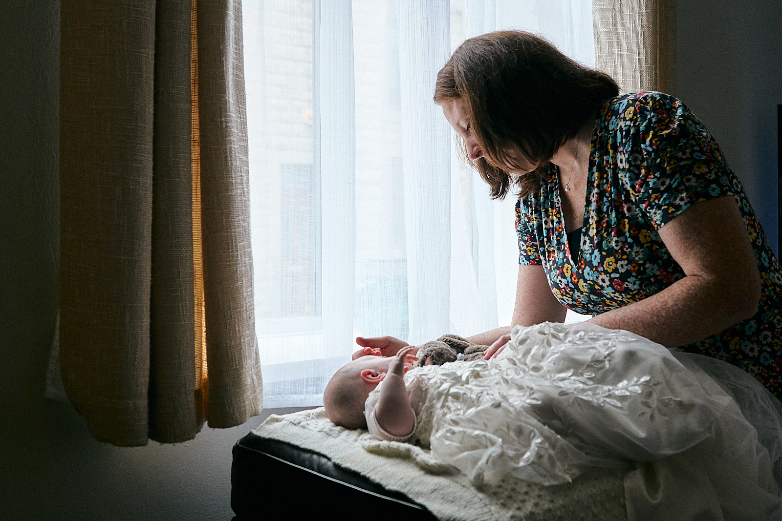 natural photo of mum stroking baby girls head asleep