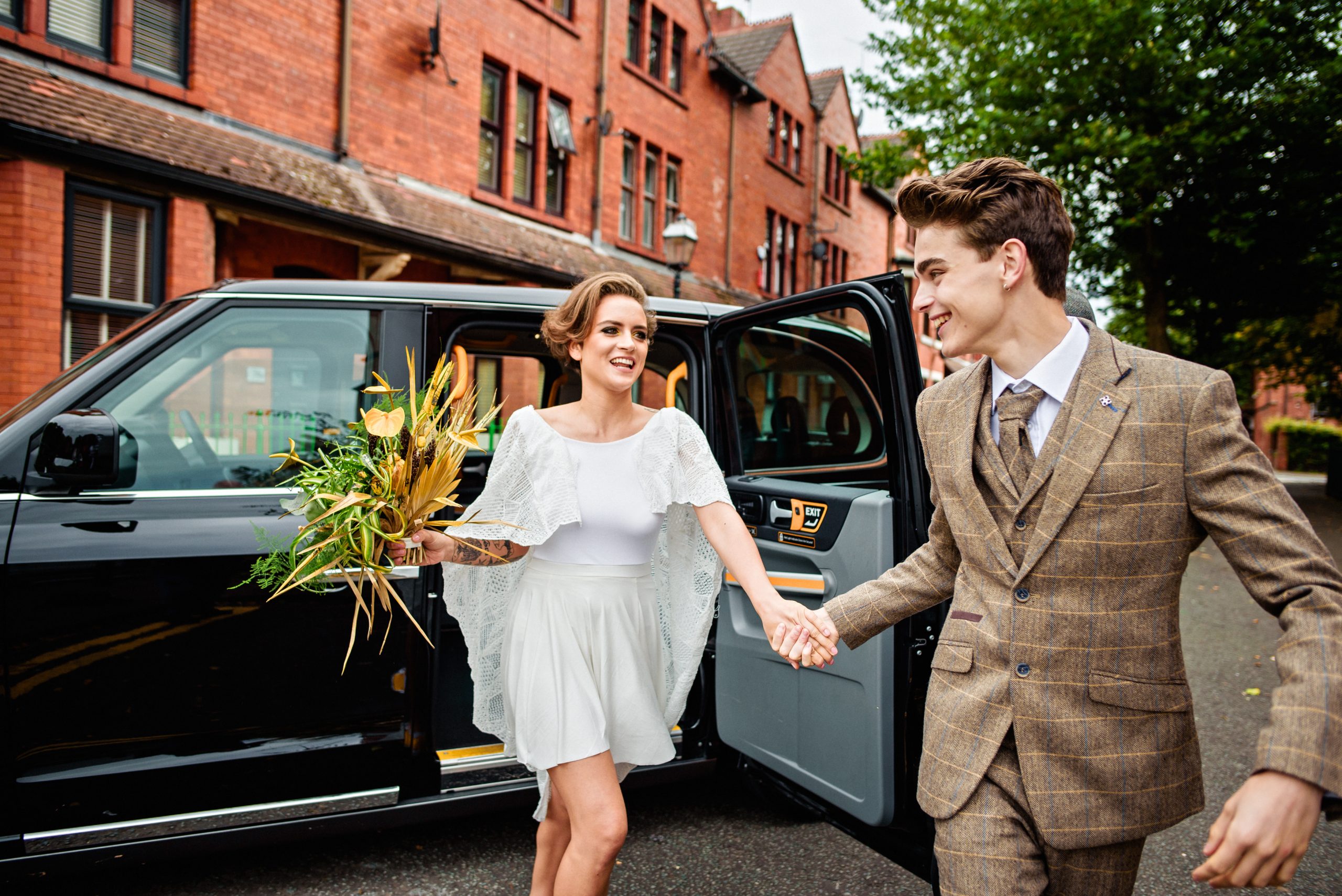 bride and groom jump out of Manchester Taxi for Salford Lads Wedding
