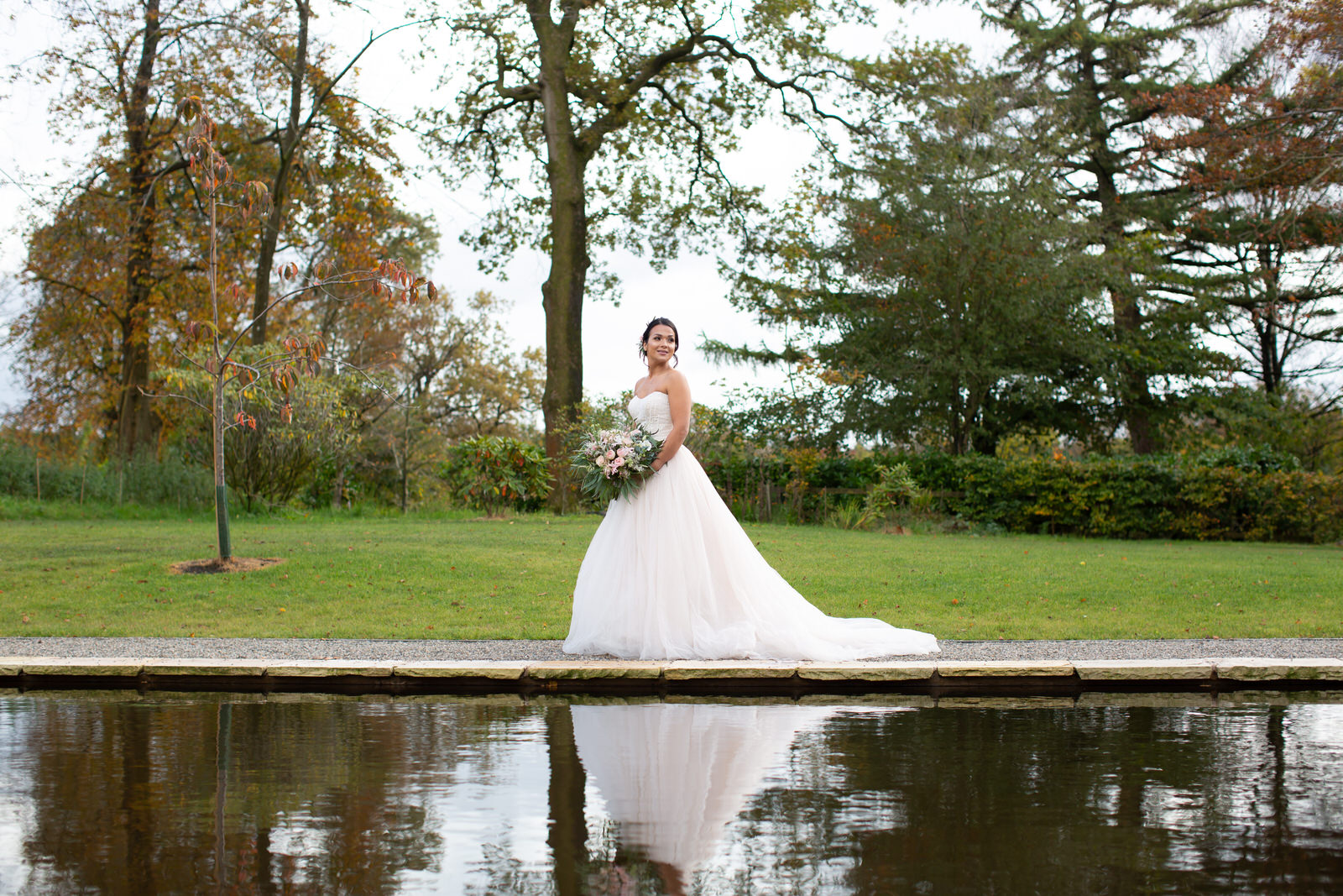 bride walks beside ceremony lily pond at Browsholme