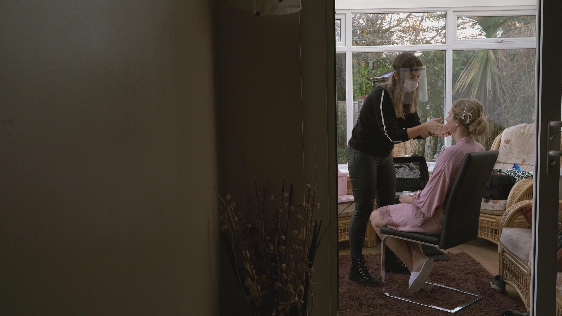 make up artist in visor applying bridal makeup in lockdown