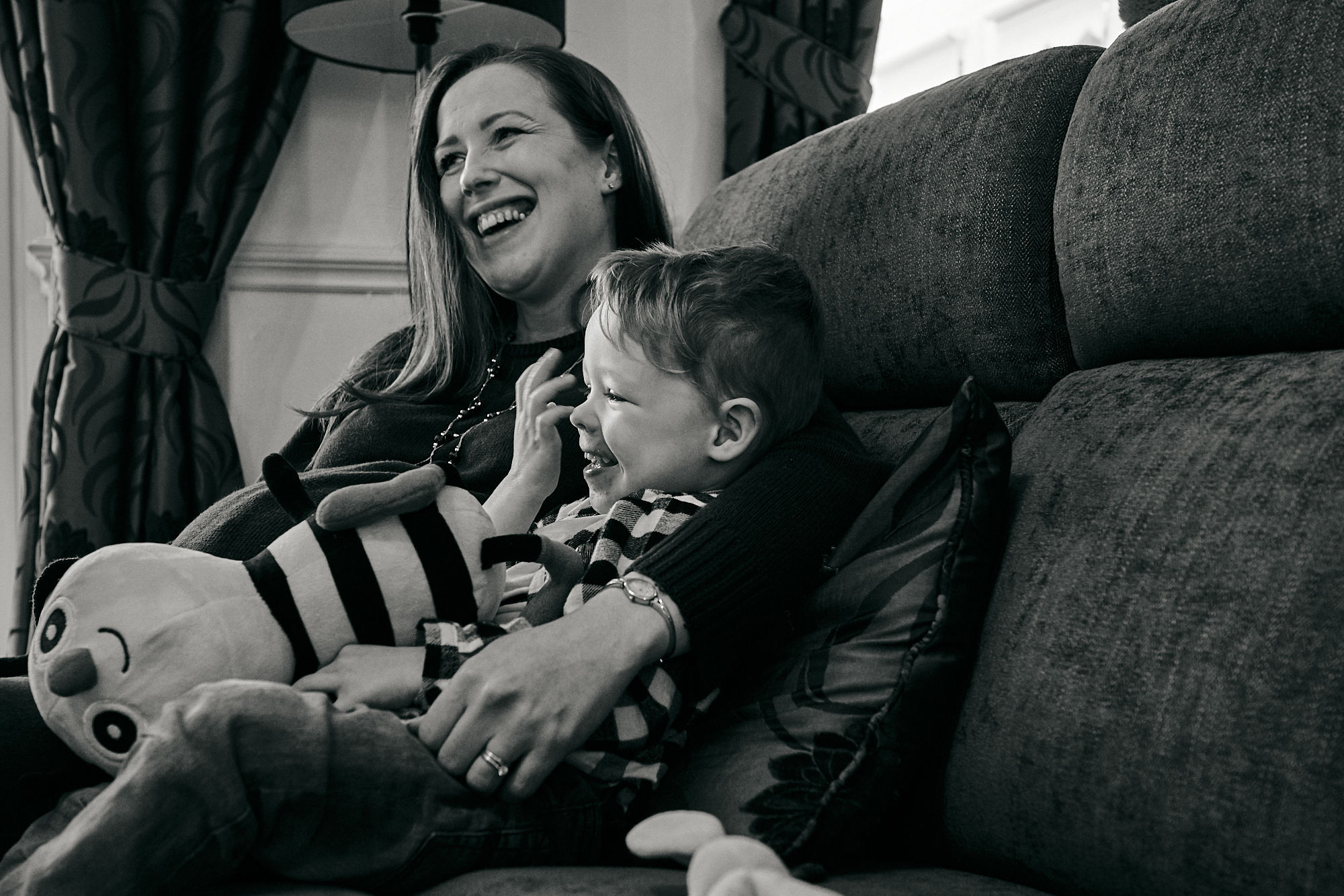 mum and son laugh on sofa during natural photoshoot