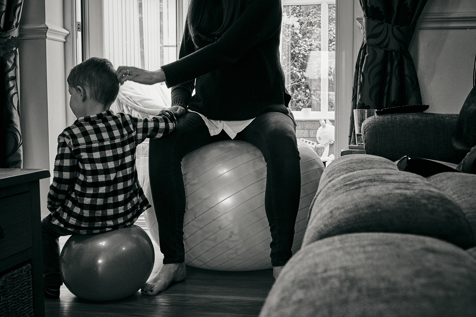 mum bouncing on pregnancy ball with son at home