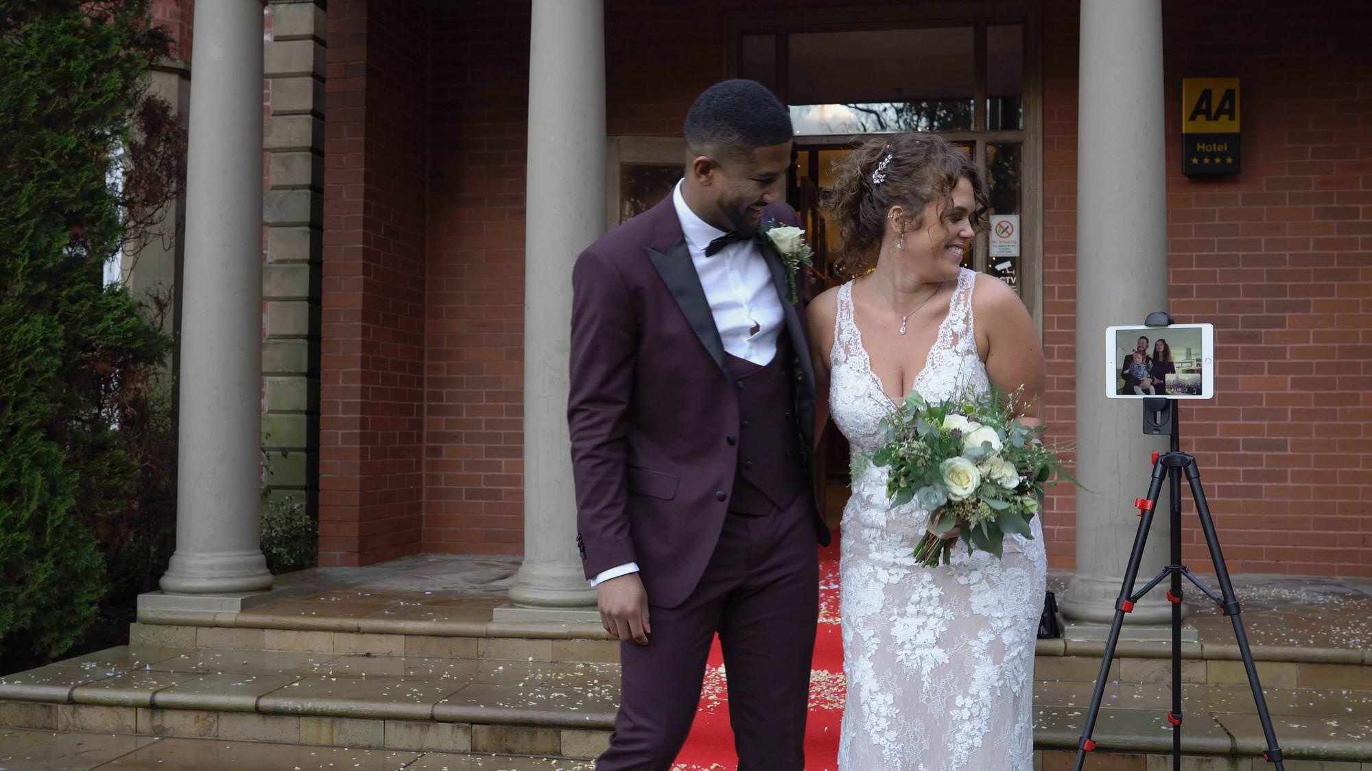 couple pose with iPad for distanced wedding photos