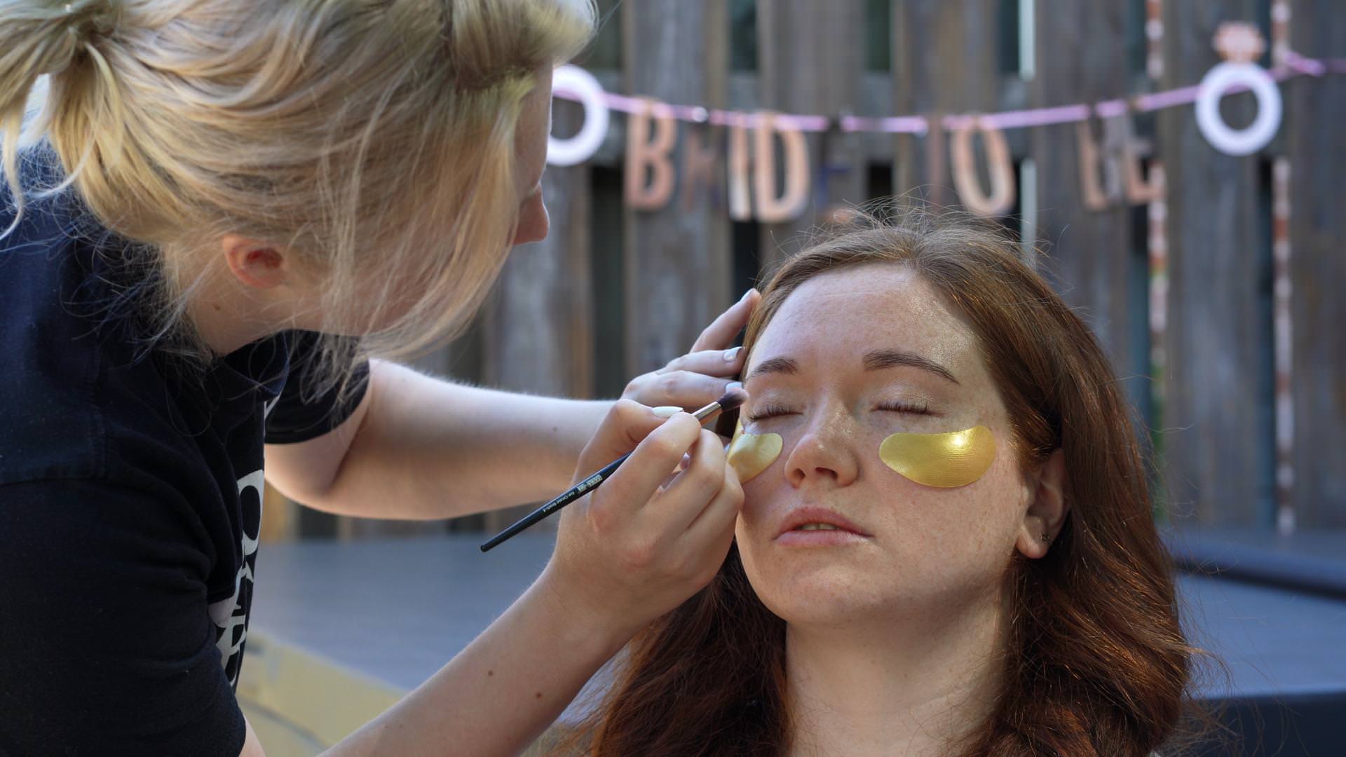 bride gets makeup done on her wedding day