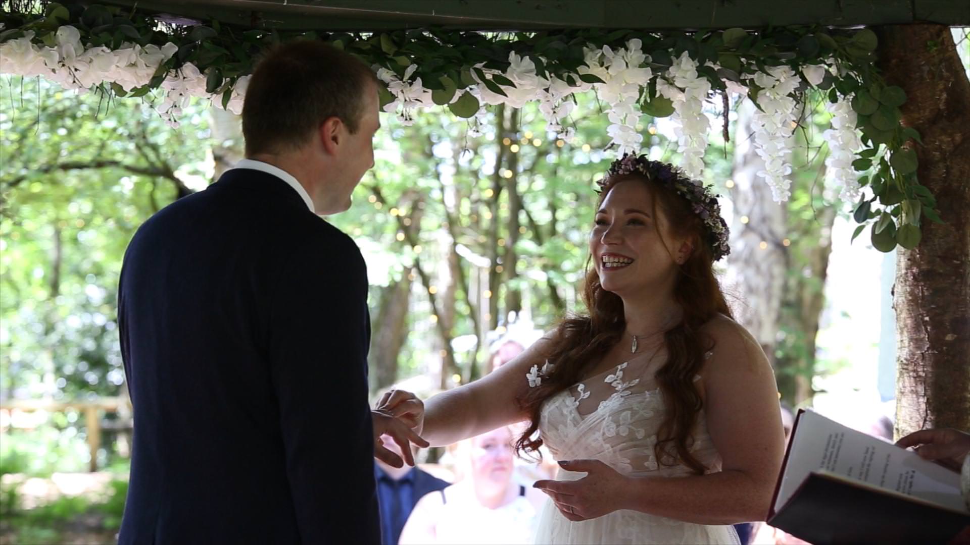 bride smiles at groom during outdoor woodland ceremony in Cheshire