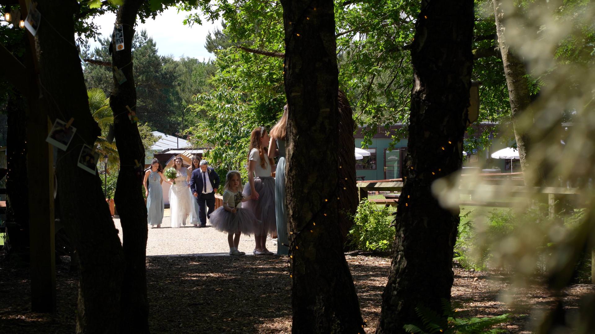 video still of bride walking to outdoor woodland ceremony