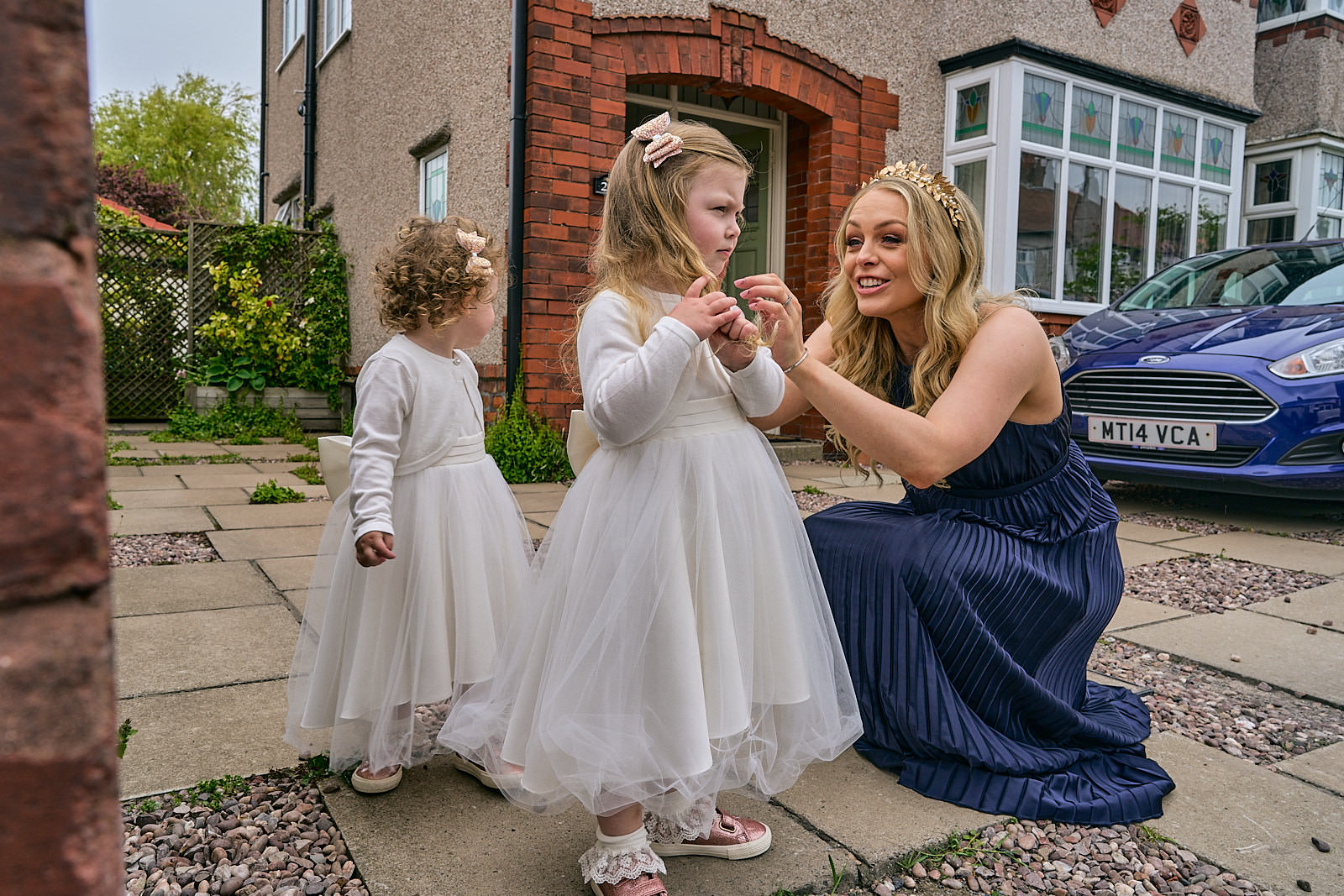 bridesmaid smiles at flowergirl outside home in crosby