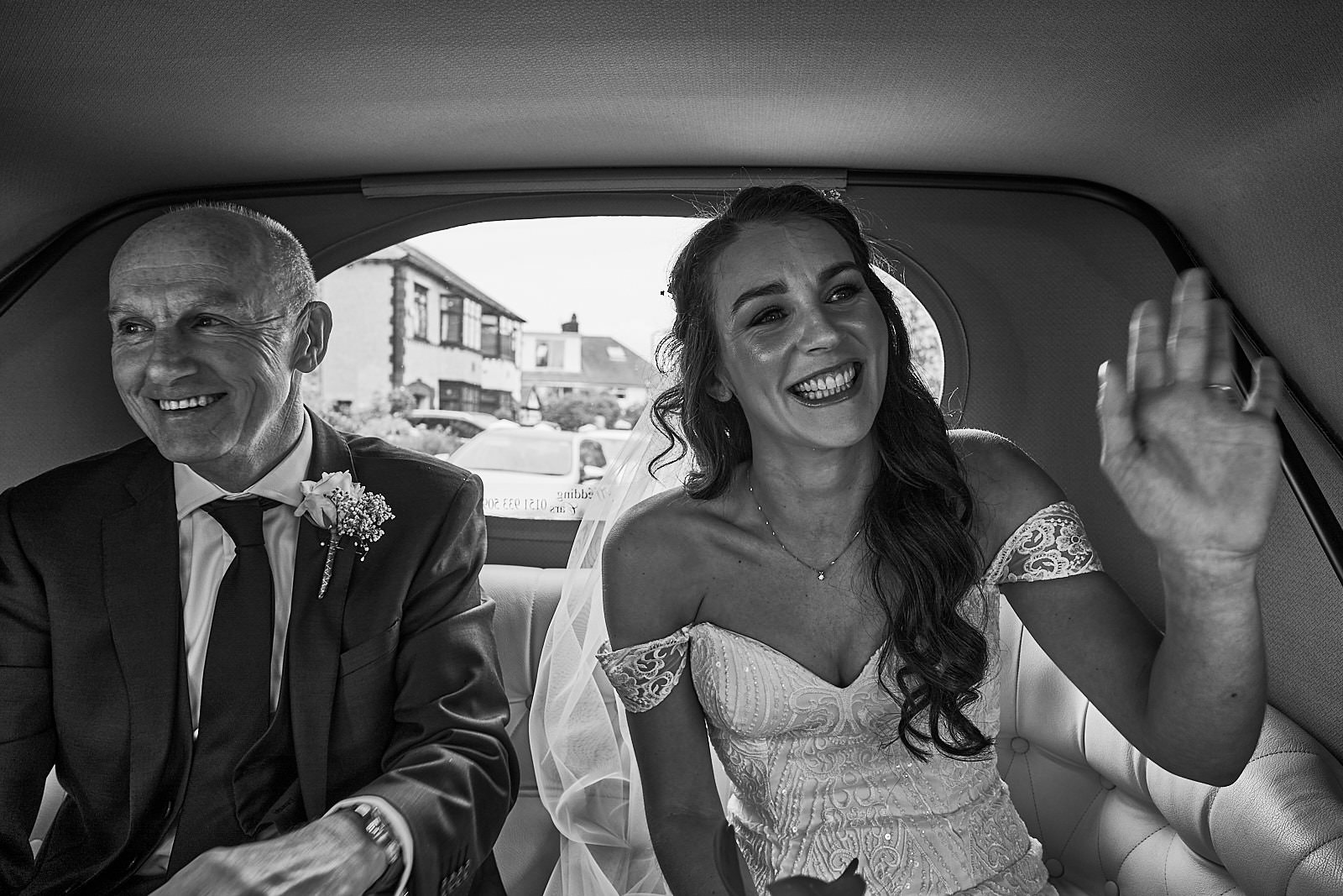 bride waves in the back of her wedding car