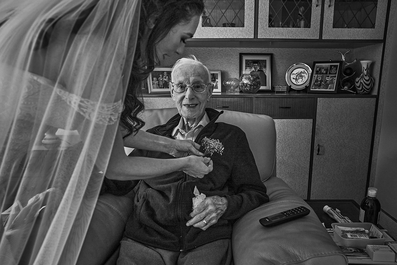bride puts button hole on grandad who can't make the wedding