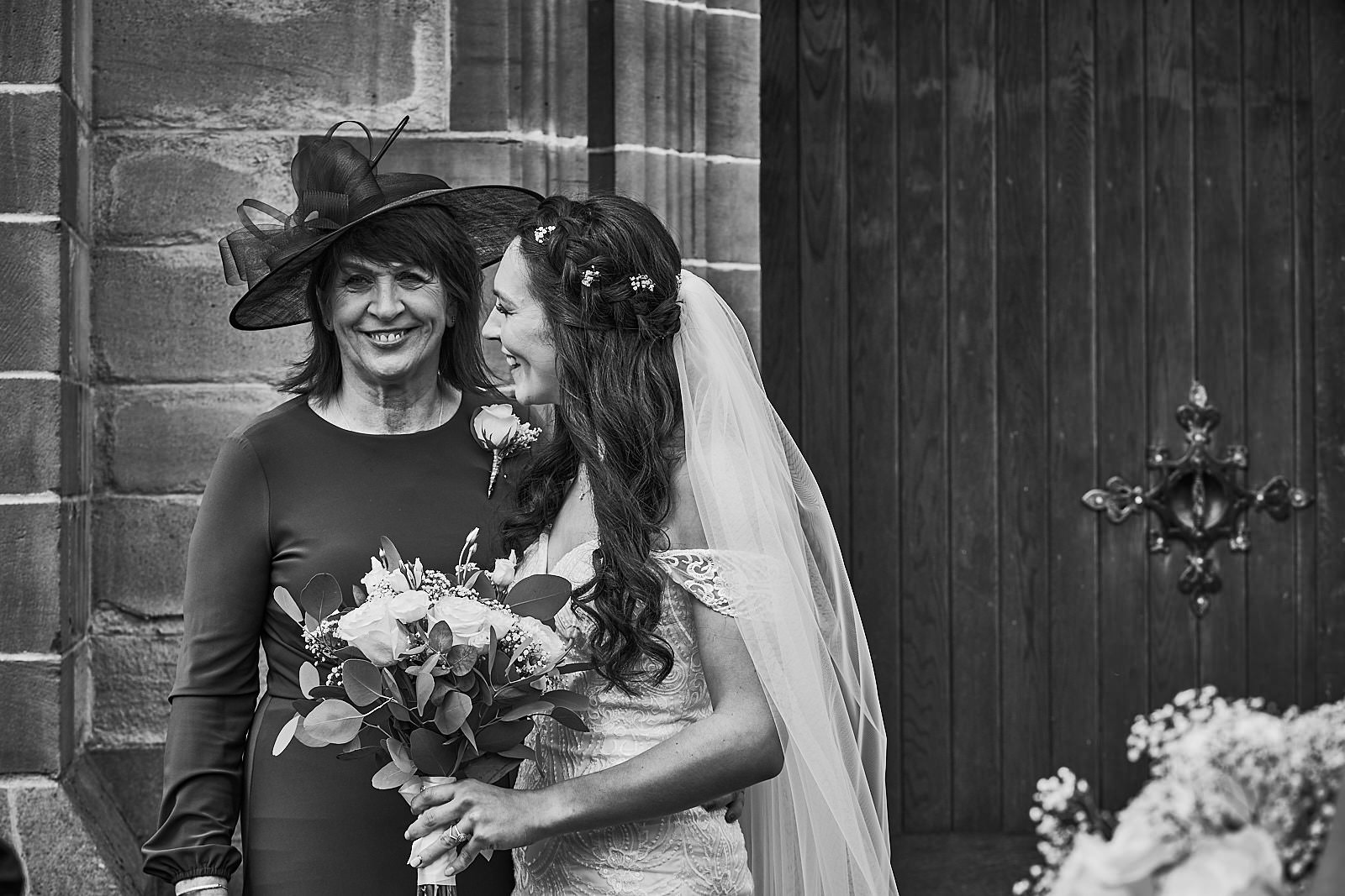 natural moment of mum and bride laughing outside church