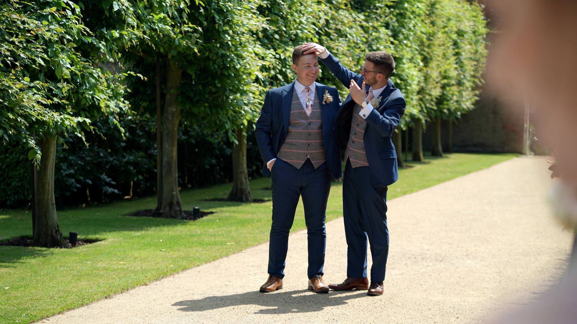 best man fixes grooms hair during formals