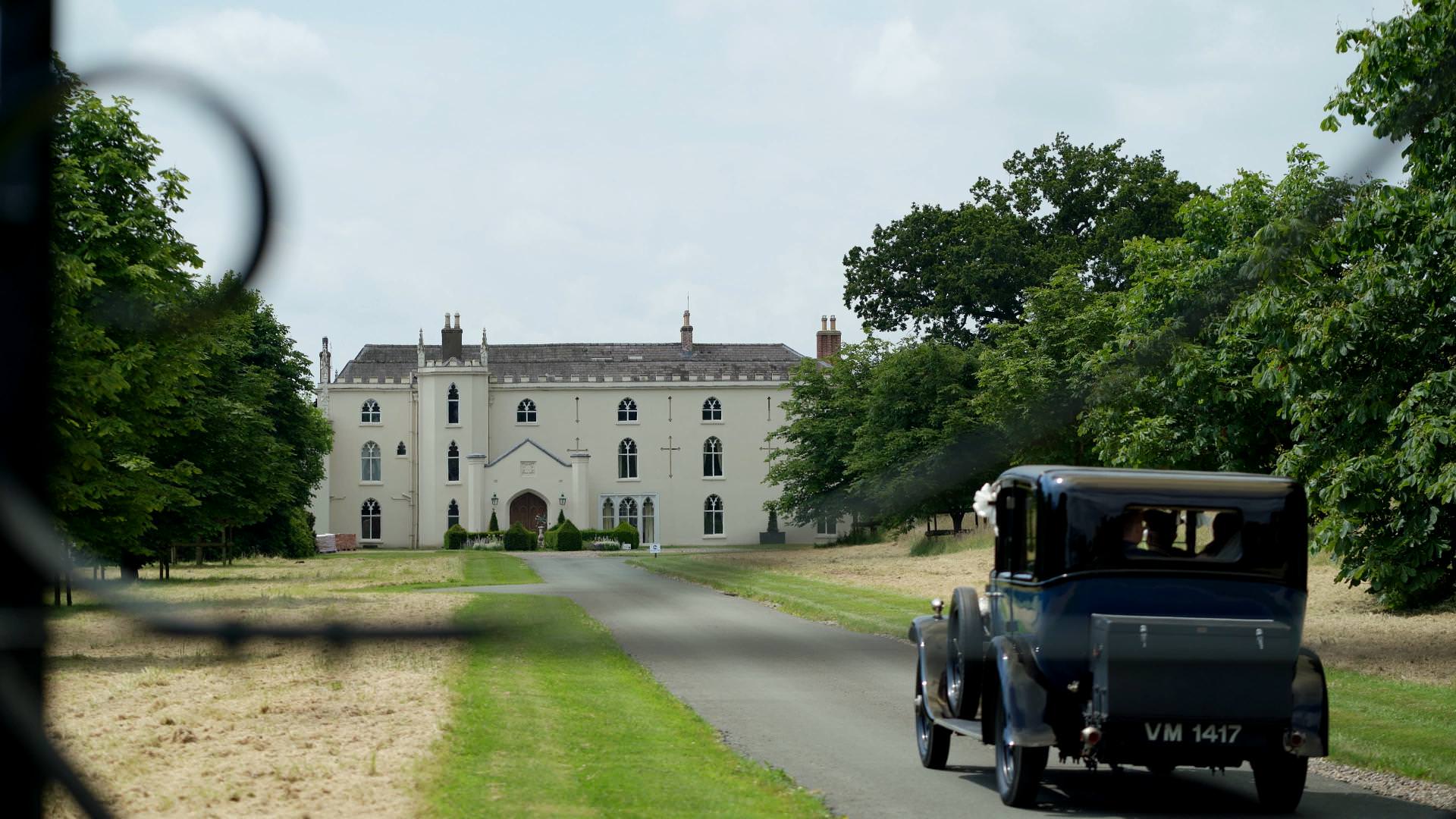 wedding car drives up to Combermere Abbey Estate