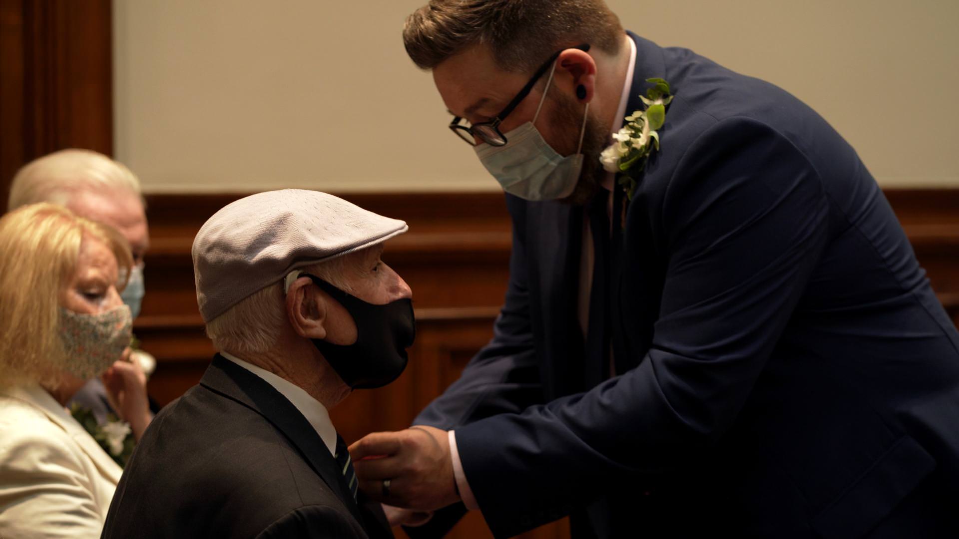 putting on buttonhole during St Georges Hall wedding