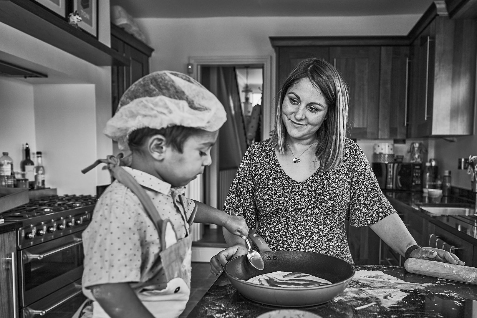 candid photo of mum and bump with toddler making pizza at home