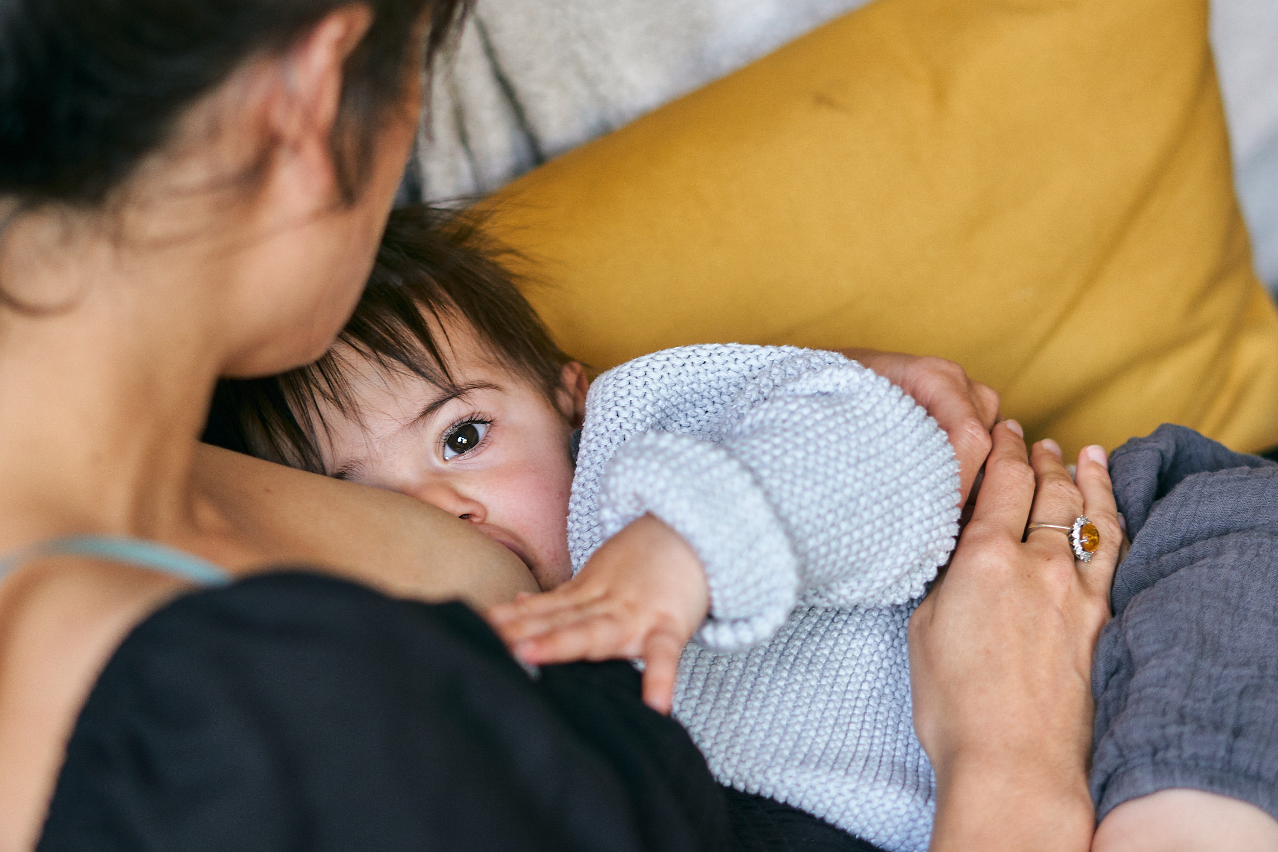candid photo of mum breastfeeding daughter at home