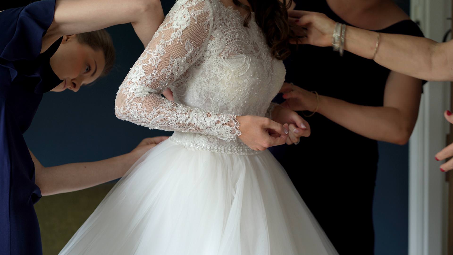 lots of hands help bride get dressed on video
