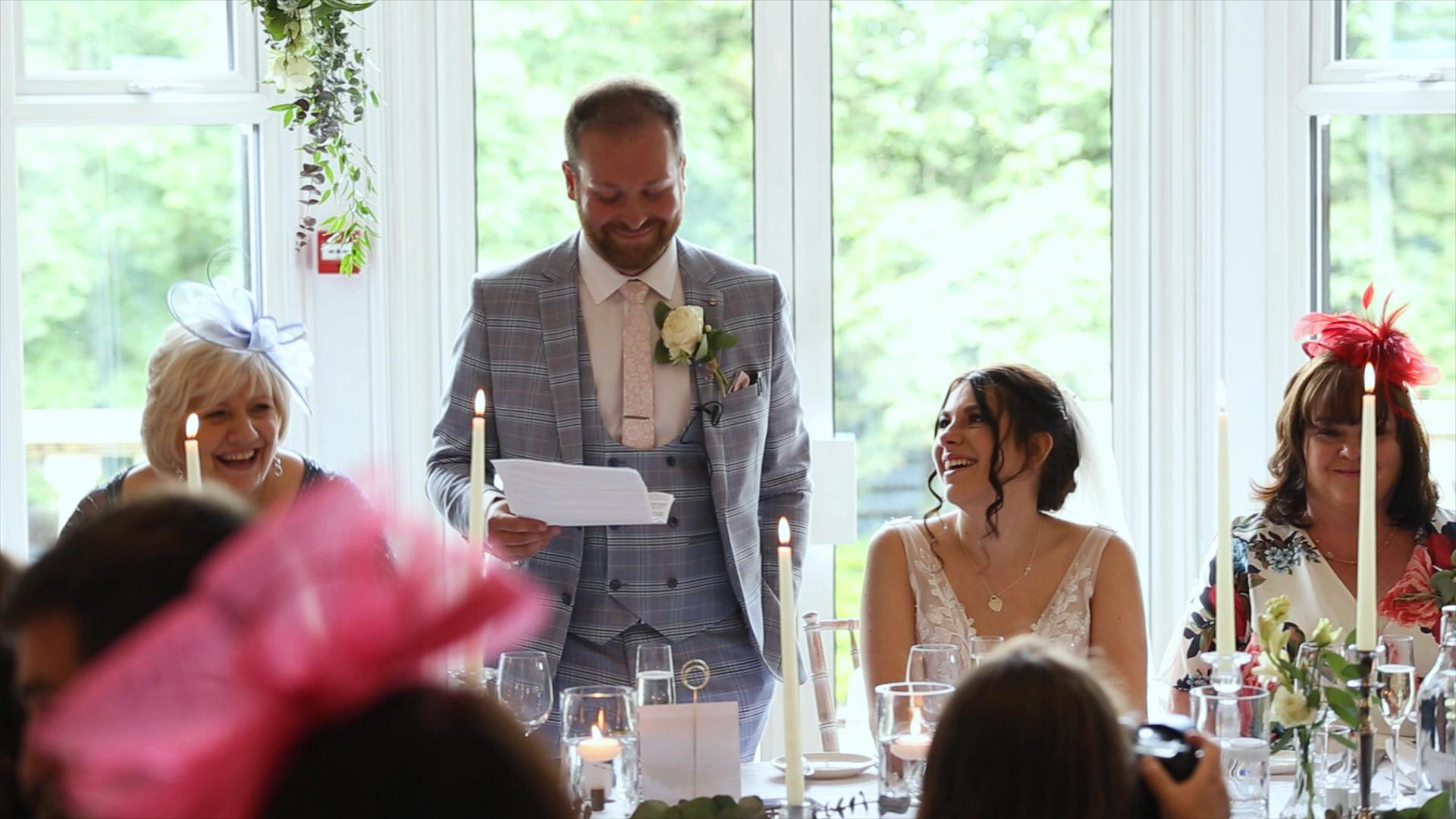 video still of bride smiling during grooms speech