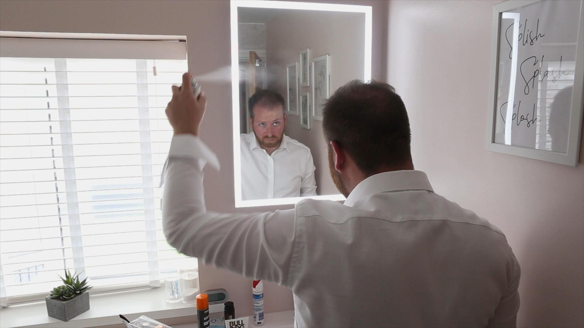 groom spraying hair on wedding morning