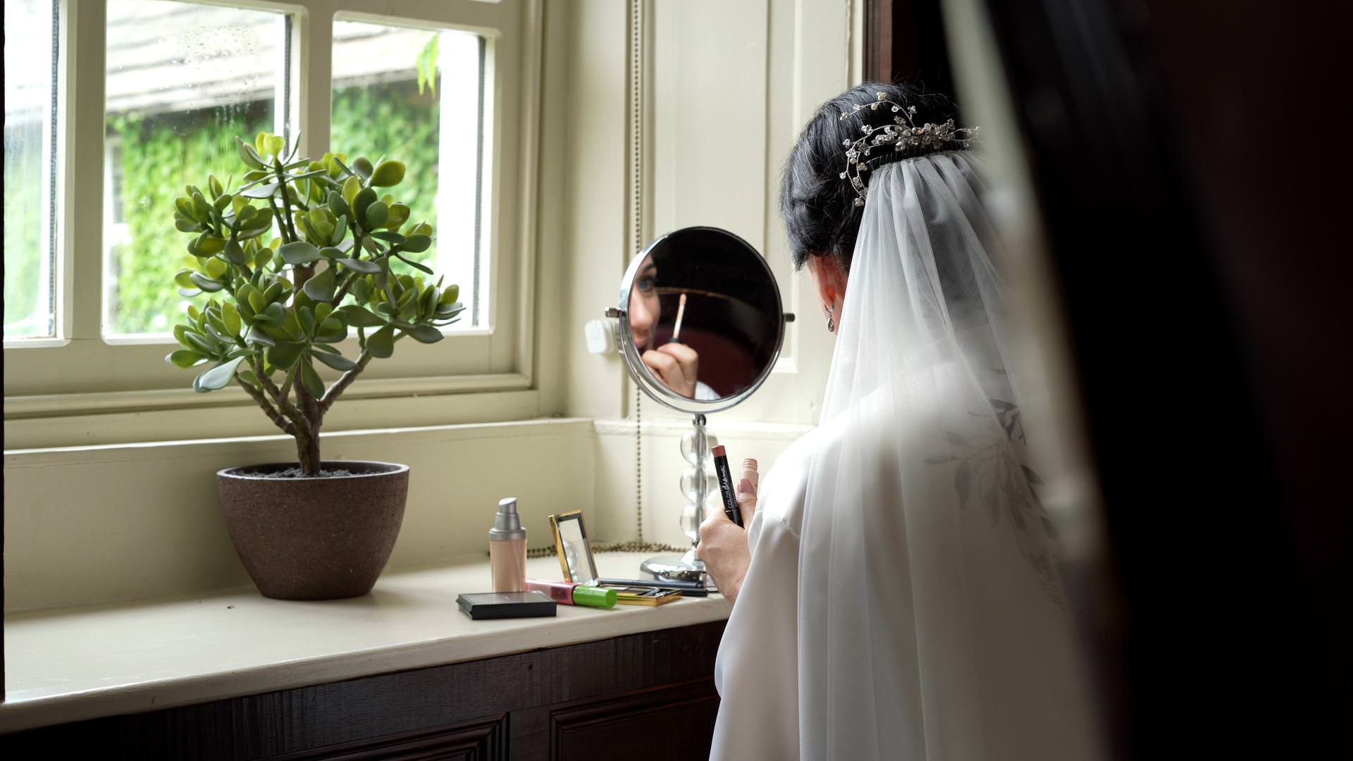 natural light video still of bride doing own makeup at Whitley