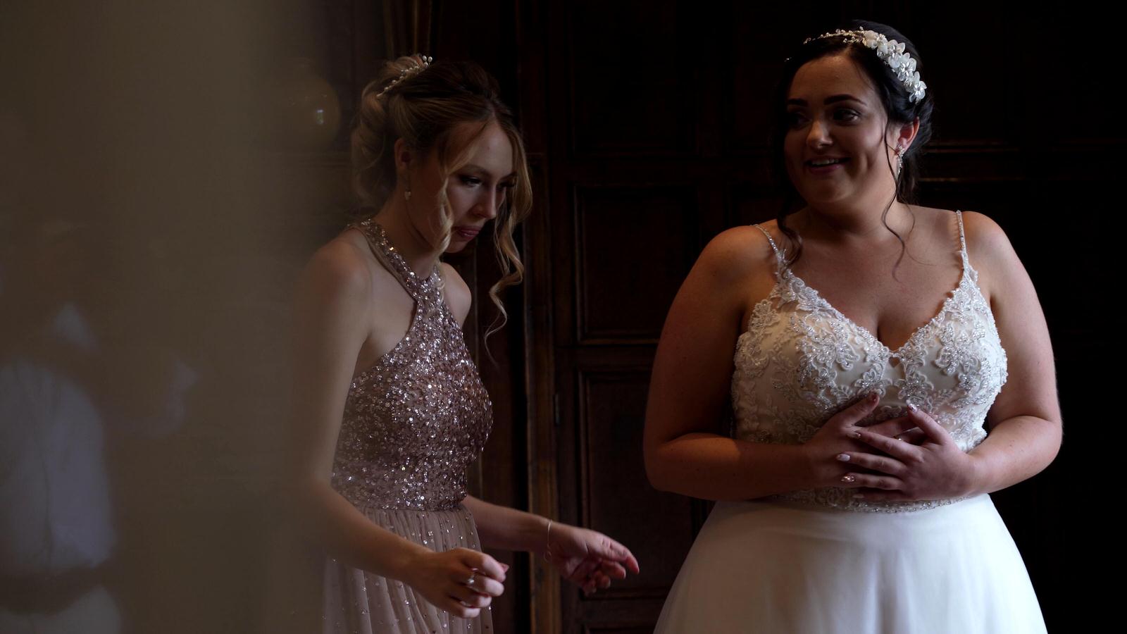 bride looks excited as she gets her wedding dress on in bridal suite