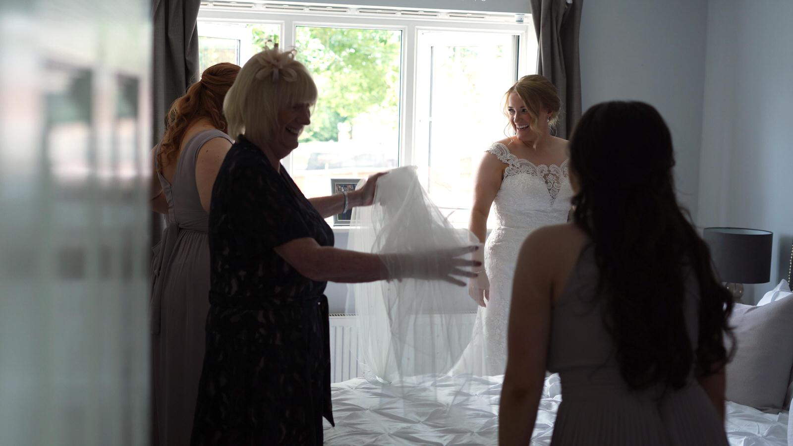 bride smiles at bridesmaids waiting for her veil