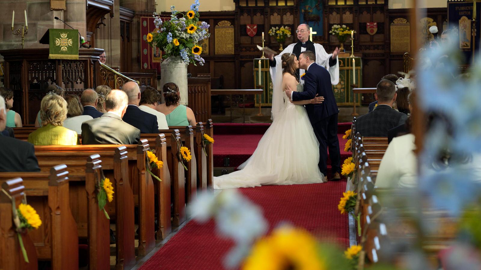 couple kiss during wedding ceremony at Barton Church