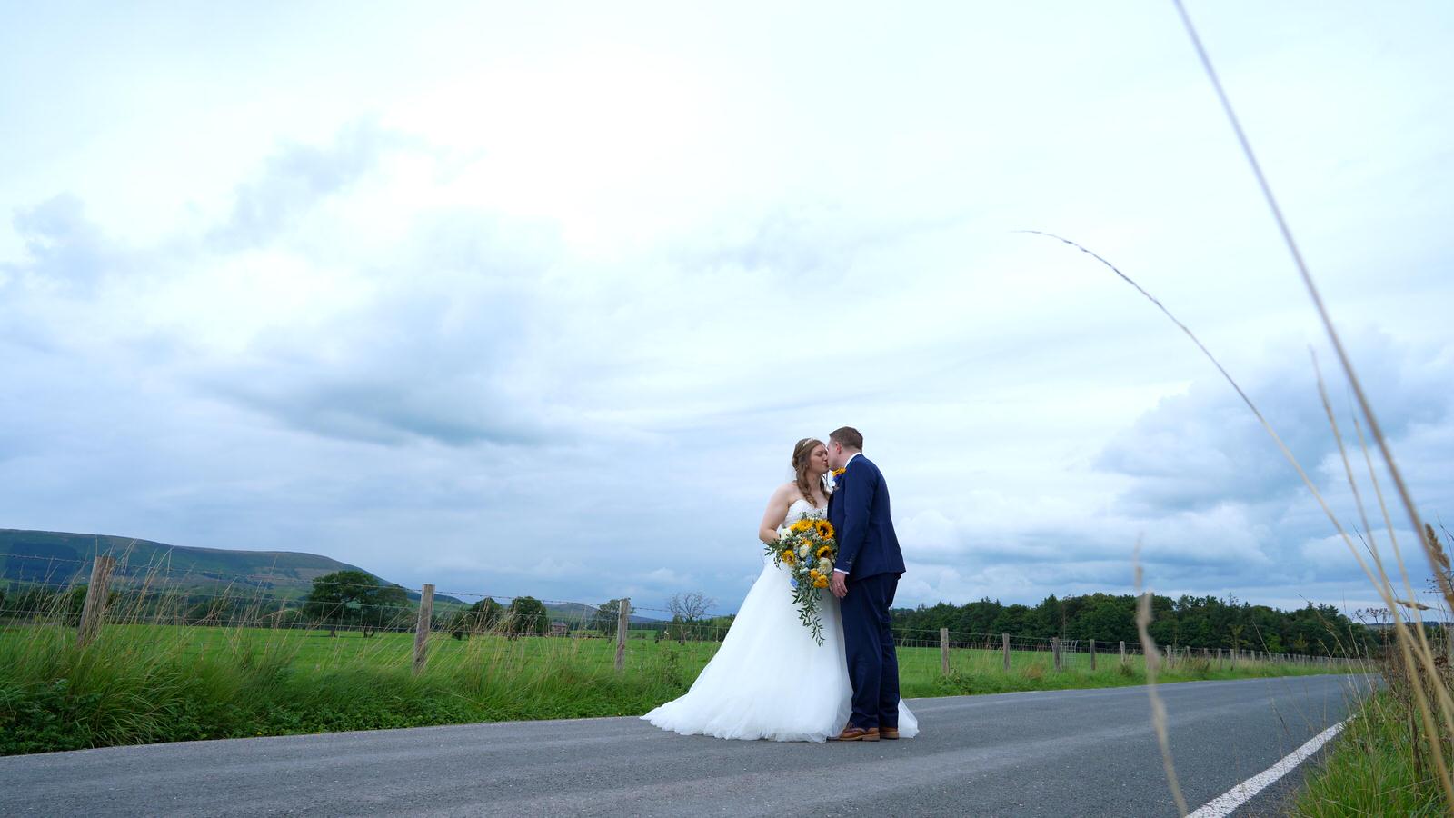 couple pose on country road with dramatic scenery