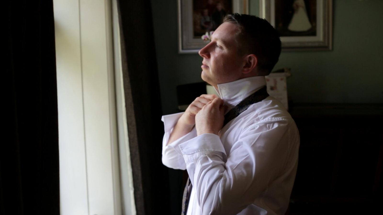 groom fixes his wedding tie