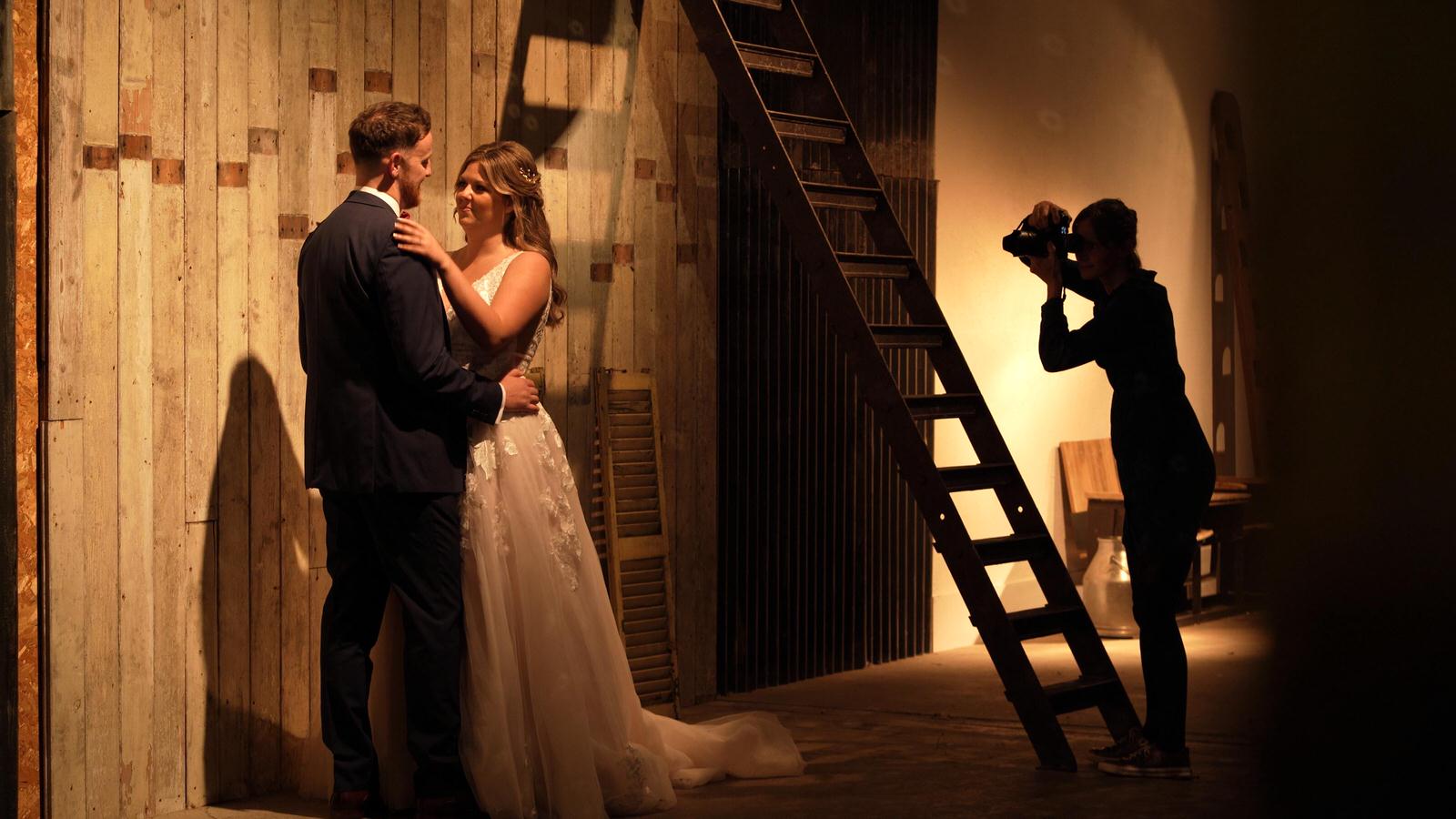 video still of photographer posing couple in shooting gallery