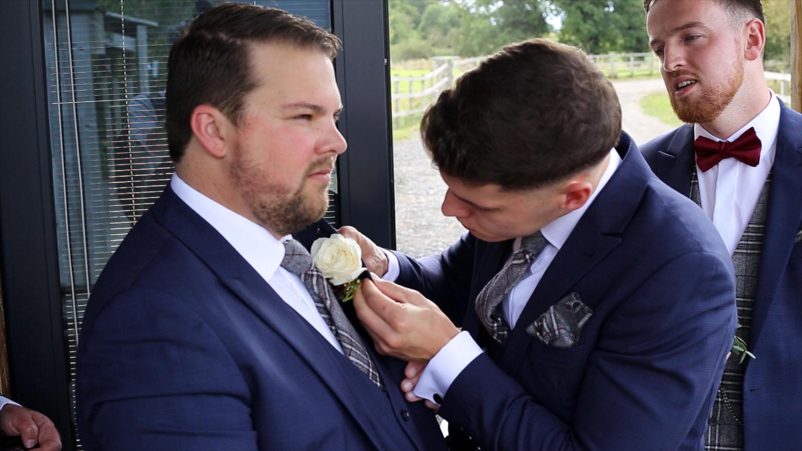 groomsmen try to attach button holes