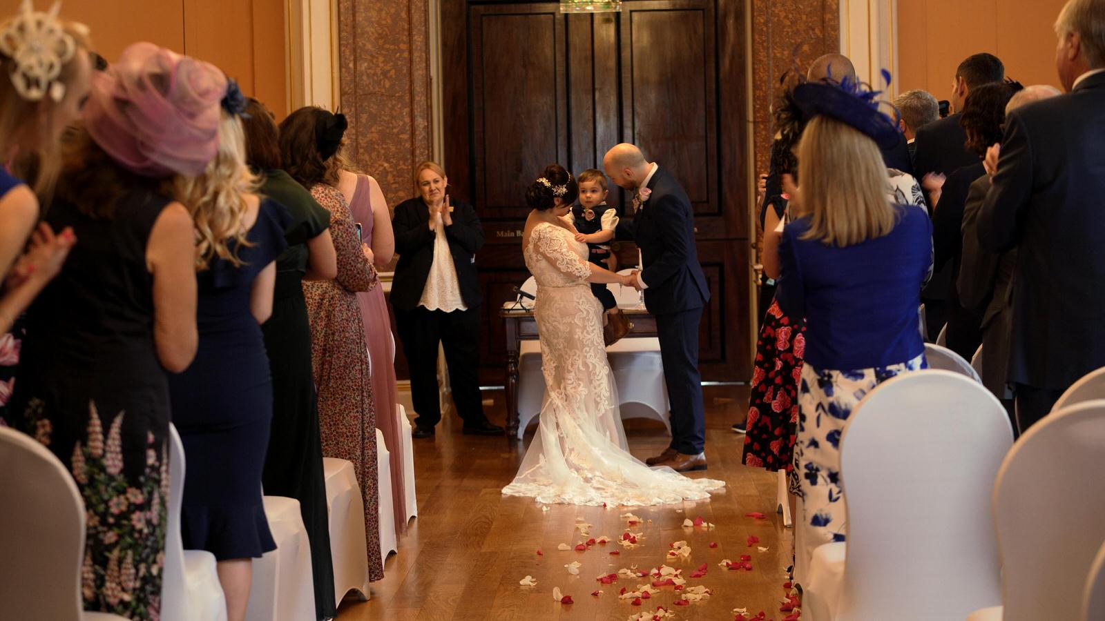 bride and groom hug son during wedding