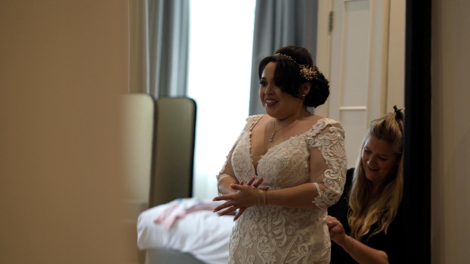 bride smiles at herself in the mirror getting ready