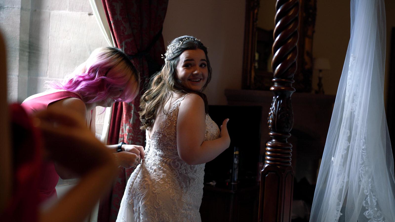 bride laughs whilst getting dressed