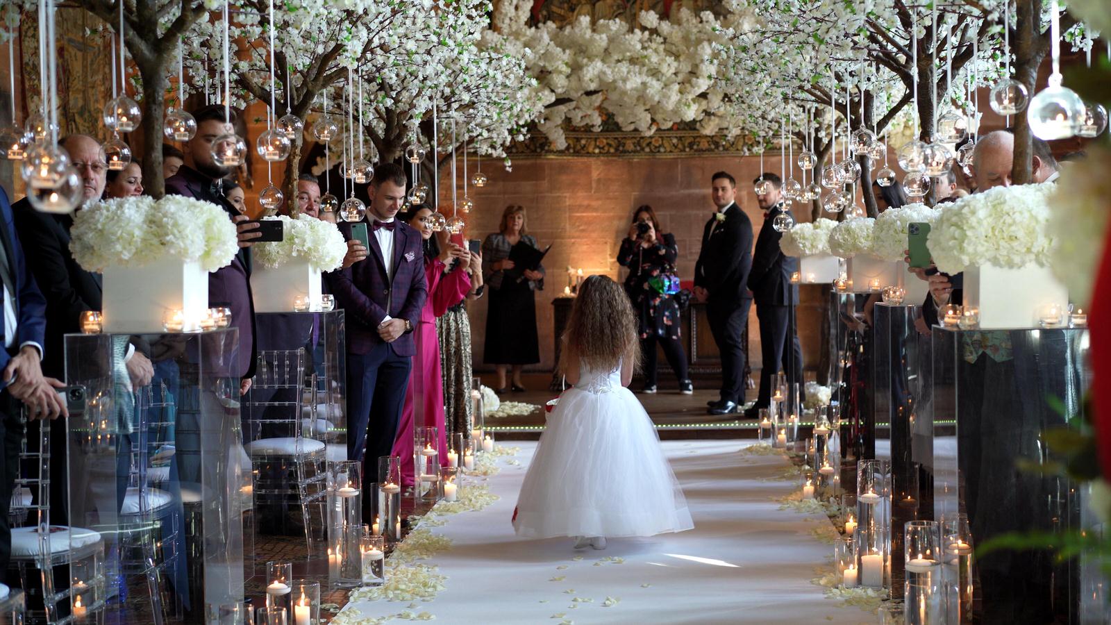 flower girl scatters petals on white carpet aisle