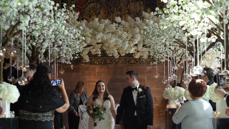 couple stand under stunning blossom tree arch