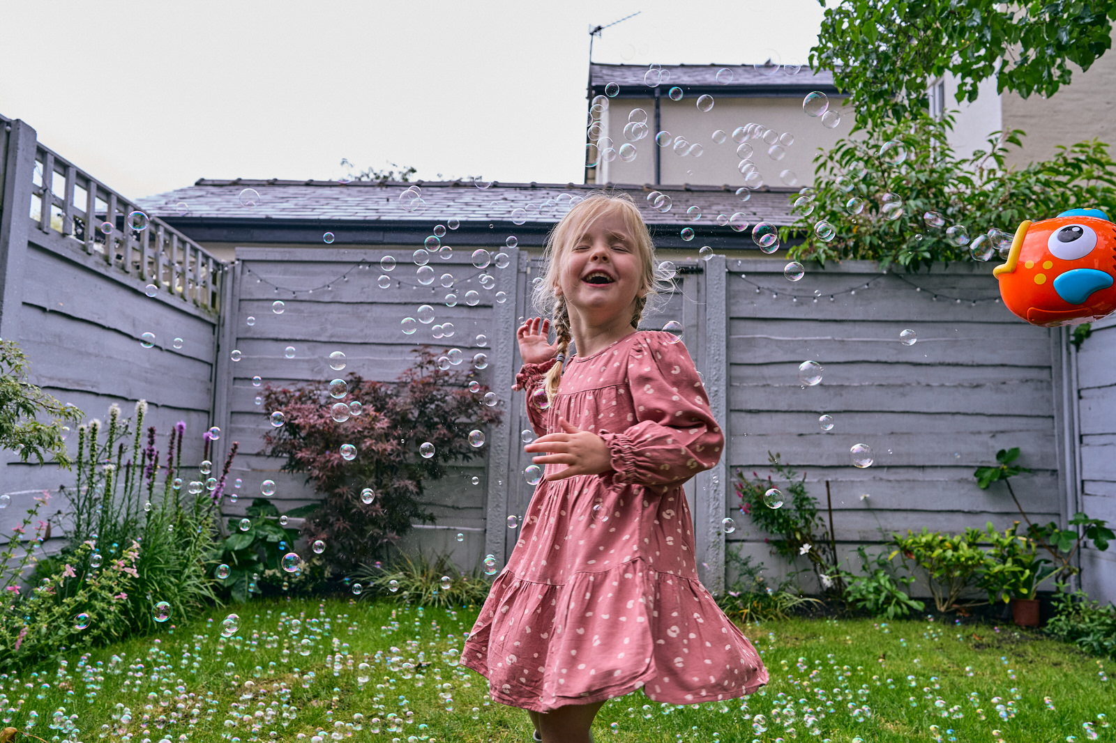child laughs at bubbles in family garden